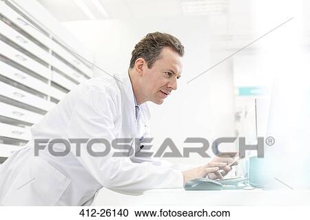 Pharmacist reviewing prescription in pharmacy View Large Photo Image Stock Image - Pharmacist reviewing prescription in pharmacy. Fotosearch
