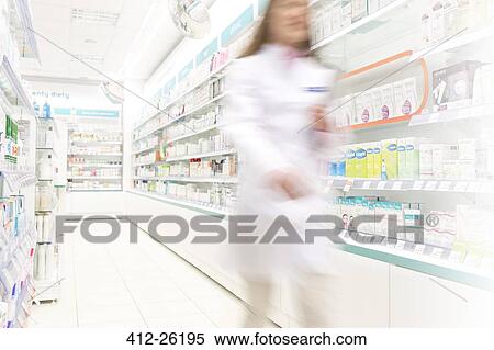Stock Photography - Pharmacist walking in aisle of pharmacy. Fotosearch