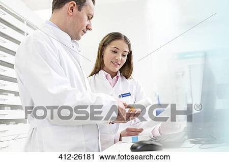 Pharmacists reviewing label on bottle in pharmacy View Large Photo Image Stock Image - Pharmacists reviewing label on bottle in pharmacy. Fotosearch