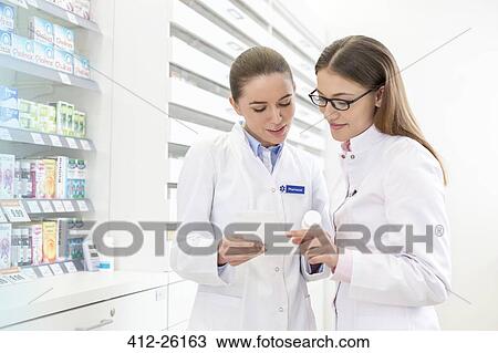 Stock Image - Pharmacists reviewing prescription in pharmacy. Fotosearch