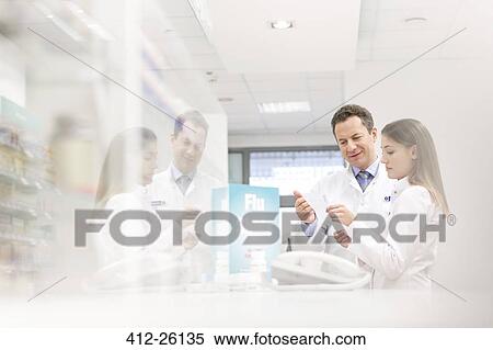 Stock Photography - Pharmacists reviewing prescription in pharmacy. Fotosearch