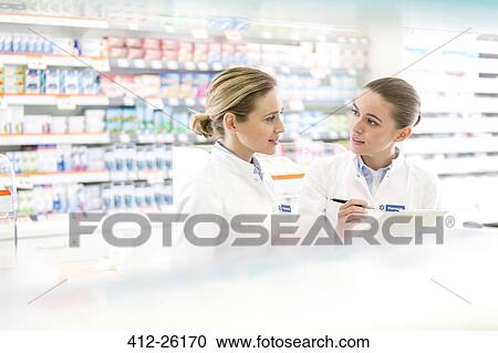 Stock Image - Pharmacists talking in pharmacy. Fotosearch
