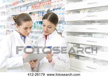 Stock Photo - Pharmacists with clipboard in pharmacy. Fotosearch
