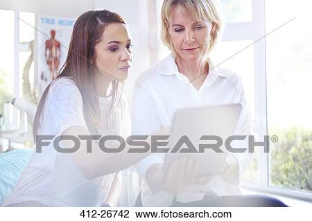 Physical therapist and patient using digital tablet in examination room View Large Photo Image Stock Image - Physical therapist and patient using digital tablet in examination room. Fotosearch