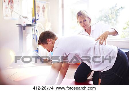 Physical therapist guiding man’s back View Large Photo Image Picture - Physical therapist guiding man’s back. Fotosearch