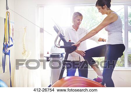 Physical therapist guiding woman on stationary bike View Large Photo Image Picture - Physical therapist guiding woman on stationary bike. Fotosearch