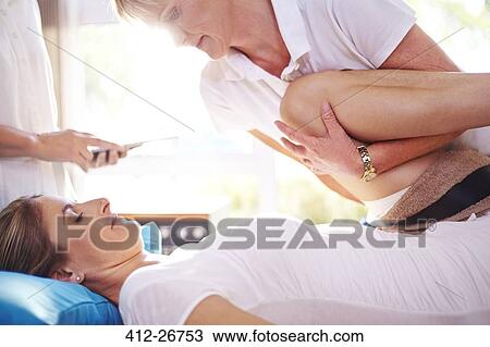 Stock Image - Physical therapist stretching woman’s leg. Fotosearch