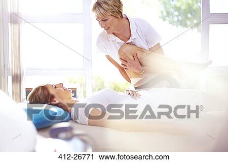 Stock Image - Physical therapist stretching woman’s leg. Fotosearch