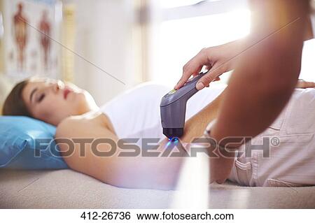 Stock Photograph - Physical therapist using ultrasound probe on woman’s arm. Fotosearch