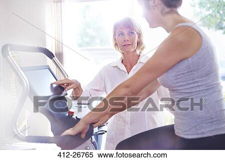 Physical therapy guiding woman on stationary bike View Large Photo Image Stock Photography - Physical therapy guiding woman on stationary bike. Fotosearch