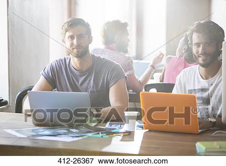 Portrait confident creative businessmen working at laptops in office View Large Photo Image Stock Photo - Portrait confident creative businessmen working at laptops in office. Fotosearch