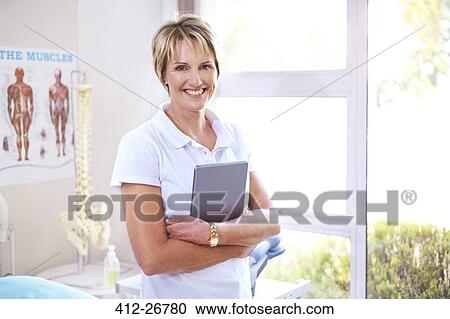 Stock Image - Portrait confident physical therapist with digital tablet in examination room. Fotosearch