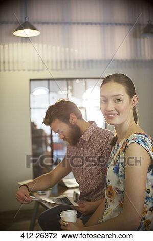 Stock Image - Portrait smiling casual businesswoman reviewing proofs with businessman in office. Fotosearch