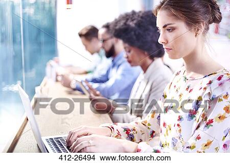 Serious businesswoman using laptop at cafe counter View Large Photo Image Picture - Serious businesswoman using laptop at cafe counter. Fotosearch