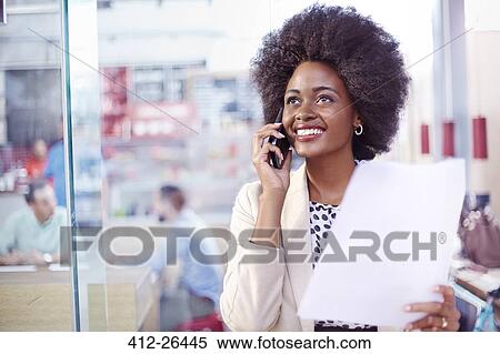 Stock Photography - Smiling businesswoman with paperwork talking on telephone. Fotosearch