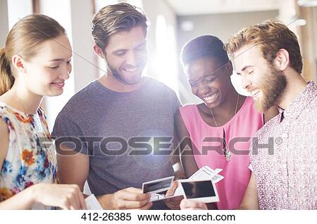 Smiling casual business people looking at instant photos View Large Photo Image Stock Photography - Smiling casual business people looking at instant photos. Fotosearch