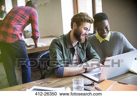 Smiling casual business people working at laptop in office View Large Photo Image Stock Image - Smiling casual business people working at laptop in office. Fotosearch