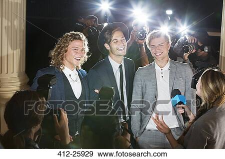 Smiling celebrities being interviewed and photographed by paparazzi photographers at event View Large Photo Image Stock Photo - Smiling celebrities being interviewed and photographed by paparazzi photographers at event. Fotosearch