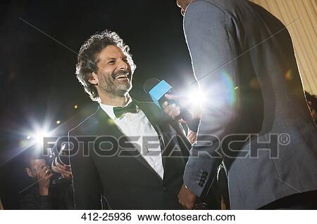 Smiling celebrity being interviewed and photographed by paparazzi at event View Large Photo Image Stock Photograph - Smiling celebrity being interviewed and photographed by paparazzi at event. Fotosearch