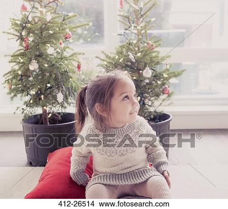 Picture - Smiling girl in front of potted trees with Christmas lights. Fotosearch