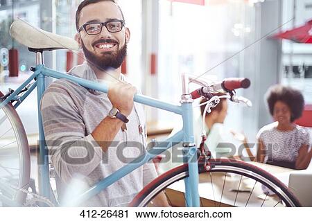 Smiling man carrying bicycle in cafe View Large Photo Image Stock Image - Smiling man carrying bicycle in cafe. Fotosearch
