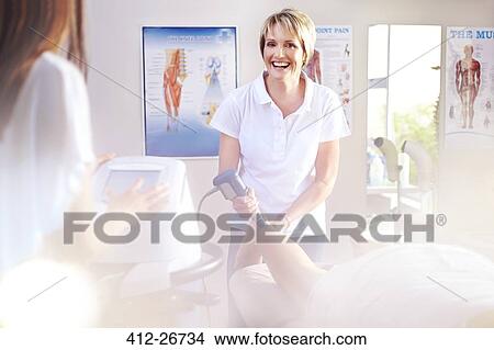 Smiling physical therapist using ultrasound probe on patient’s leg View Large Photo Image Picture - Smiling physical therapist using ultrasound probe on patient’s leg. Fotosearch