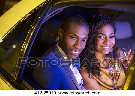 Well-dressed couple drinking champagne inside limousine View Large Photo Image Stock Image - Well-dressed couple drinking champagne inside limousine. Fotosearch