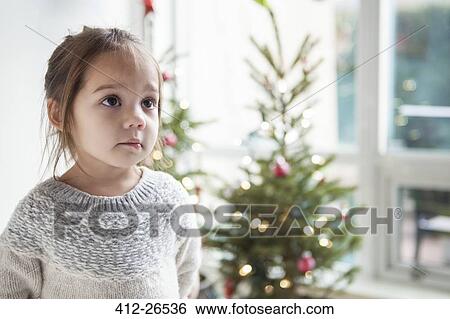 Wide-eyed girl looking up in front of Christmas tree View Large Photo Image Stock Photograph - Wide-eyed girl looking up in front of Christmas tree. Fotosearch