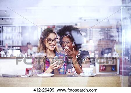 Women laughing and drinking coffee in cafe window View Large Photo Image Stock Photo - Women laughing and drinking coffee in cafe window. Fotosearch