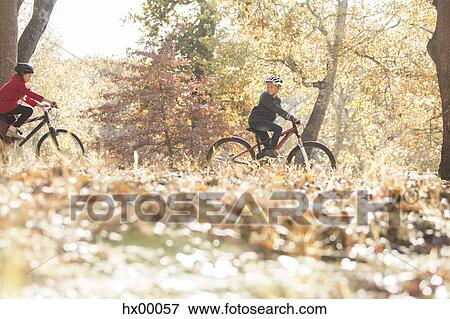 Boy and girl bike riding in woods with autumn leaves View Large Photo Image Stock Photo - Boy and girl bike riding in woods with autumn leaves. Fotosearch