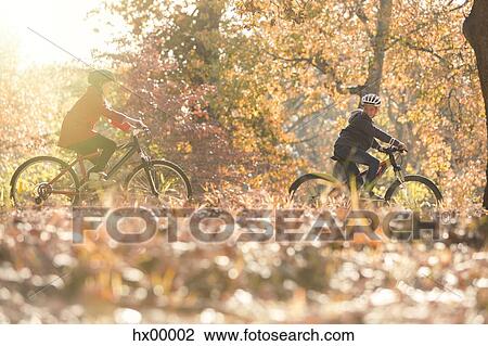 Boy and girl riding bikes in autumn leaves View Large Photo Image Stock Image - Boy and girl riding bikes in autumn leaves. Fotosearch