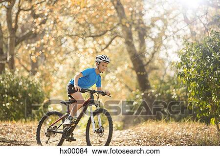 Picture - Boy mountain biking on path in woods. Fotosearch