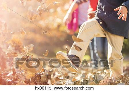 Stock Photography - Boy running and jumping in autumn leaves. Fotosearch