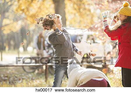 Stock Photo - Boy throwing autumn leaves at girl in park. Fotosearch