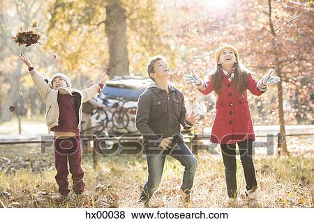 Boys and girl throwing autumn leaves overhead in woods View Large Photo Image Stock Photo - Boys and girl throwing autumn leaves overhead in woods. Fotosearch