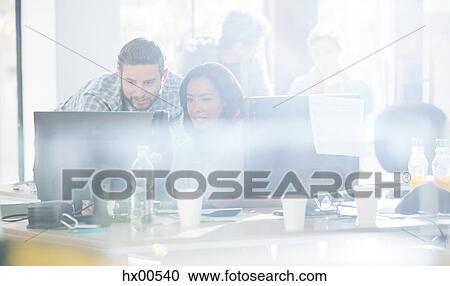 Stock Image - Business people using computer in sunny office. Fotosearch
