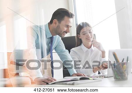 Businessman and businesswoman working at laptop in office View Large Photo Image Stock Image - Businessman and businesswoman working at laptop in office. Fotosearch