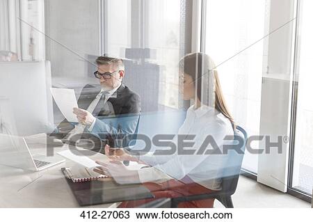 Stock Image - Businessman and businesswoman working in conference room. Fotosearch