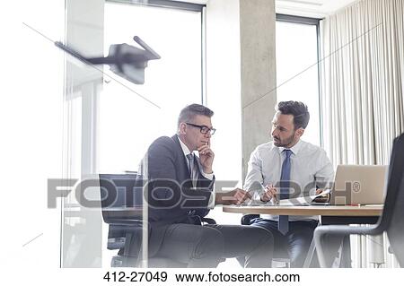 Businessmen reviewing and discussing report in conference room View Large Photo Image Stock Photo - Businessmen reviewing and discussing report in conference room. Fotosearch