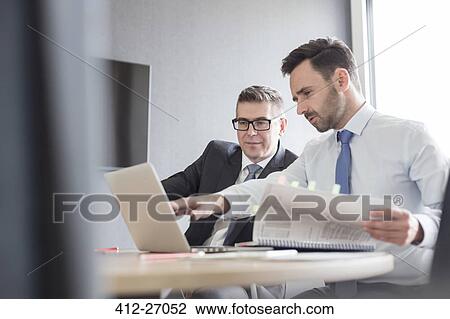Businessmen with report working at laptop in office View Large Photo Image Stock Image - Businessmen with report working at laptop in office. Fotosearch
