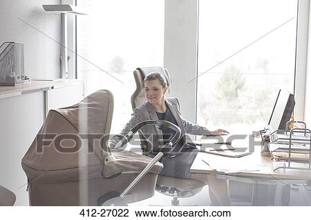 Businesswoman checking baby carriage in office View Large Photo Image Stock Image - Businesswoman checking baby carriage in office. Fotosearch