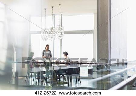 Stock Image - Businesswoman presenting to coworkers in sunny conference room. Fotosearch