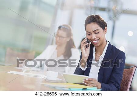 Businesswoman talking on cell phone and using digital tablet in office View Large Photo Image Stock Photography - Businesswoman talking on cell phone and using digital tablet in office. Fotosearch