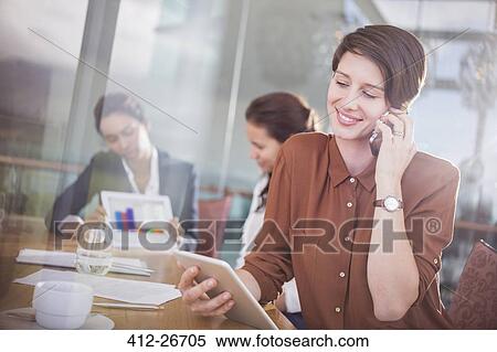 Businesswoman talking on cell phone and using digital tablet in office View Large Photo Image Stock Photography - Businesswoman talking on cell phone and using digital tablet in office. Fotosearch