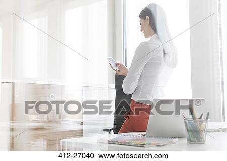 Businesswoman texting with cell phone in office View Large Photo Image Stock Image - Businesswoman texting with cell phone in office. Fotosearch
