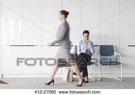 Businesswoman texting with cell phone in lobby behind walking businesswoman on the move View Large Photo Image Stock Image - Businesswoman texting with cell phone in lobby behind walking businesswoman on the move. Fotosearch