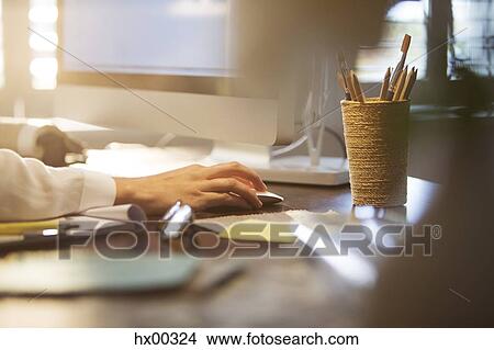 Picture - Businesswoman using computer and computer mouse at desk. Fotosearch