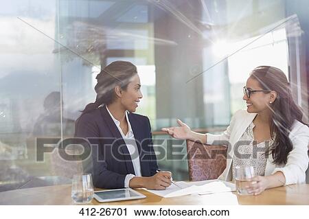 Businesswomen talking in sunny conference room View Large Photo Image Stock Image - Businesswomen talking in sunny conference room. Fotosearch