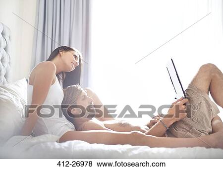 Casual couple relaxing with laptop on bed View Large Photo Image Stock Photo - Casual couple relaxing with laptop on bed. Fotosearch