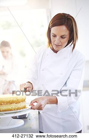 Stock Image - Chef frosting cake in kitchen. Fotosearch